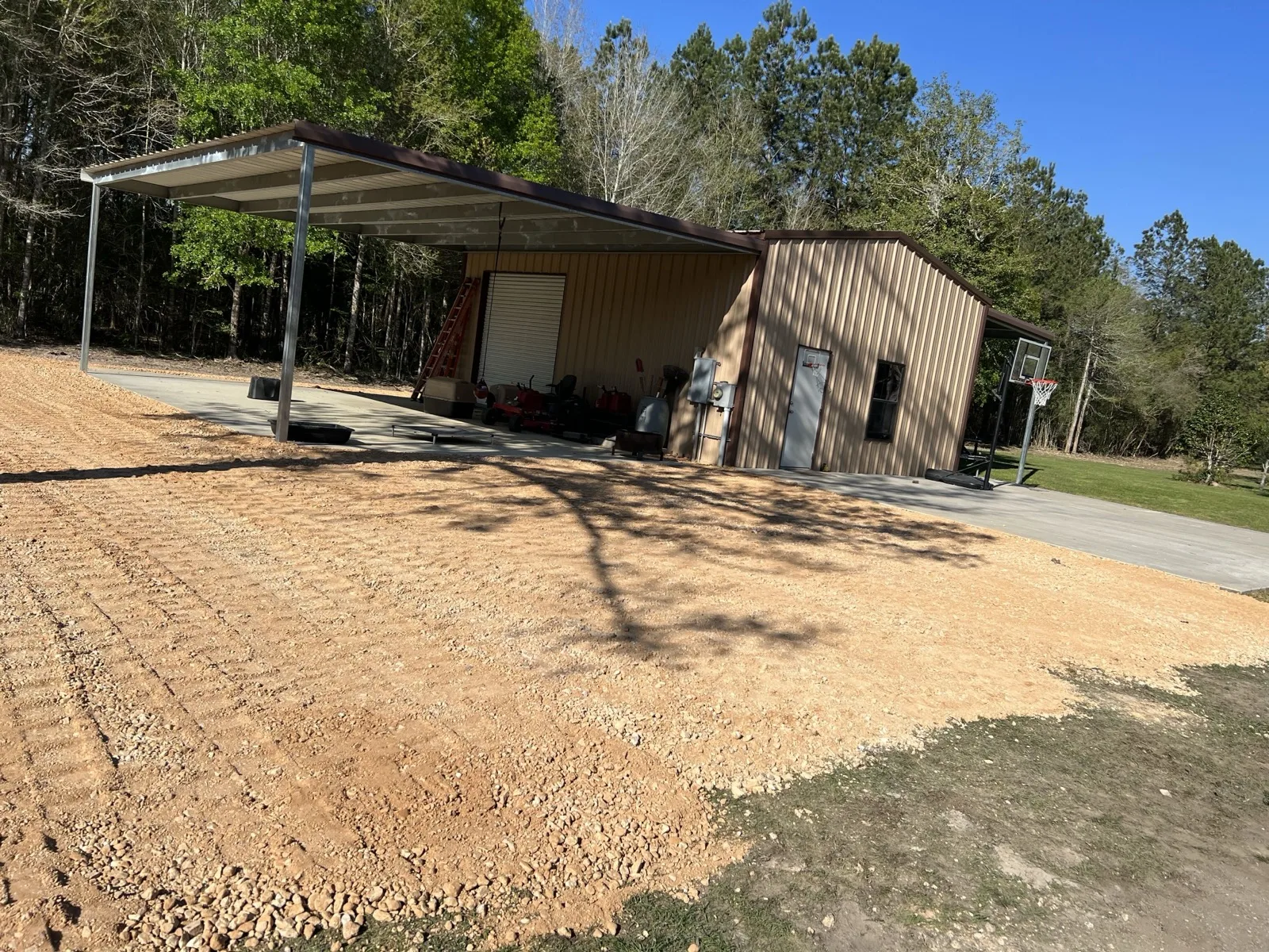 Fresh gravel pad spread beside a metal shop